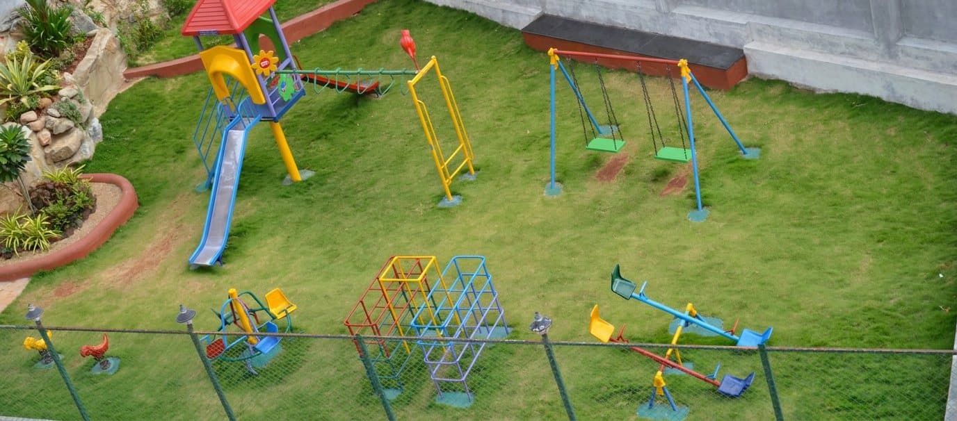 The children's play area: climbing frame with a slide, swings, seesaws and a lawn
