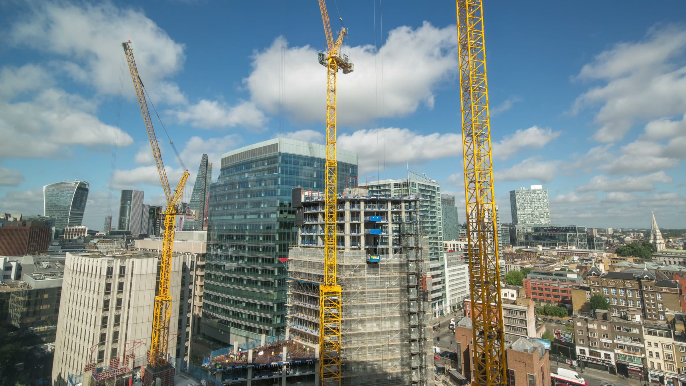 Tower cranes working above a city skyline under construction